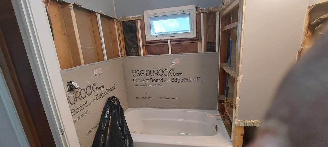 Bathtub alcove prepped with cement backer board ahead of tile, plumbing roughed in